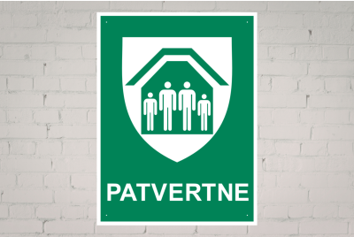 Balta ķieģeļu siena, uz kuras ir zīme "Patvertne"